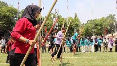 Şenlikli kalabalık ve ulusal gururla heyecanlı bir takım oyunu. Erkekler, Endonezya Bağımsızlık Günü kutlamaları sırasında 14 Ağustos 2025 'te Pekalongan, Orta Java' da geleneksel bir bakiak yarışında yarışıyorlar..