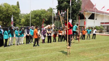 Şenlikli kalabalık ve ulusal gururla heyecanlı bir takım oyunu. Erkekler, Endonezya Bağımsızlık Günü kutlamaları sırasında 14 Ağustos 2025 'te Pekalongan, Orta Java' da geleneksel bir bakiak yarışında yarışıyorlar..