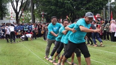 Şenlikli kalabalık ve ulusal gururla heyecanlı bir takım oyunu. Erkekler, Endonezya Bağımsızlık Günü kutlamaları sırasında 14 Ağustos 2025 'te Pekalongan, Orta Java' da geleneksel bir bakiak yarışında yarışıyorlar..