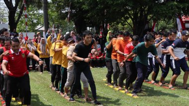 Şenlikli kalabalık ve ulusal gururla heyecanlı bir takım oyunu. Erkekler, Endonezya Bağımsızlık Günü kutlamaları sırasında 14 Ağustos 2025 'te Pekalongan, Orta Java' da geleneksel bir bakiak yarışında yarışıyorlar..