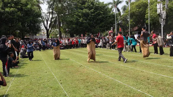 14 Ağustos 2025 'te Pekalongan, Central Java' da düzenlenen Bağımsızlık Günü kutlamalarında kadın ve erkeklerin çuval yarışı yarışına katıldığı editör fotoğrafı. Neşeli takım çalışması ve yerel gelenek.