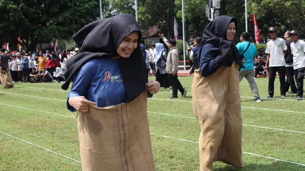 14 Ağustos 2025 'te Pekalongan, Central Java' da düzenlenen Bağımsızlık Günü kutlamalarında kadın ve erkeklerin çuval yarışı yarışına katıldığı editör fotoğrafı. Neşeli takım çalışması ve yerel gelenek.