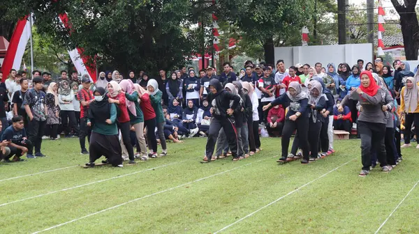 Şenlikli kalabalık ve ulusal gururla heyecanlı bir takım oyunu. Erkekler, Endonezya Bağımsızlık Günü kutlamaları sırasında 14 Ağustos 2025 'te Pekalongan, Orta Java' da geleneksel bir bakiak yarışında yarışıyorlar..