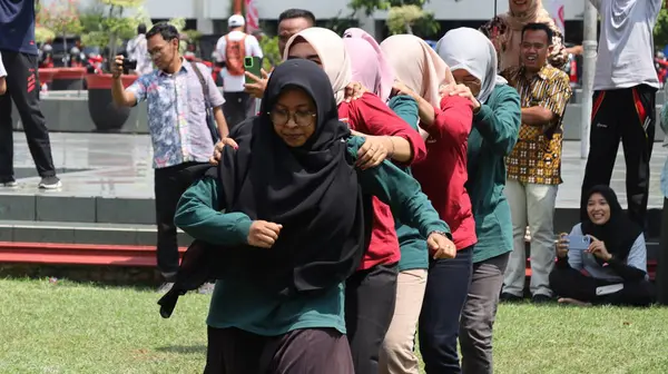 Şenlikli kalabalık ve ulusal gururla heyecanlı bir takım oyunu. Erkekler, Endonezya Bağımsızlık Günü kutlamaları sırasında 14 Ağustos 2025 'te Pekalongan, Orta Java' da geleneksel bir bakiak yarışında yarışıyorlar..