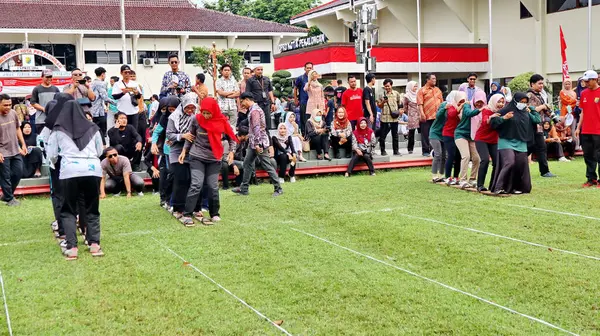 Şenlikli kalabalık ve ulusal gururla heyecanlı bir takım oyunu. Erkekler, Endonezya Bağımsızlık Günü kutlamaları sırasında 14 Ağustos 2025 'te Pekalongan, Orta Java' da geleneksel bir bakiak yarışında yarışıyorlar..