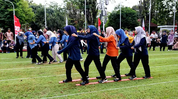 Şenlikli kalabalık ve ulusal gururla heyecanlı bir takım oyunu. Erkekler, Endonezya Bağımsızlık Günü kutlamaları sırasında 14 Ağustos 2025 'te Pekalongan, Orta Java' da geleneksel bir bakiak yarışında yarışıyorlar..