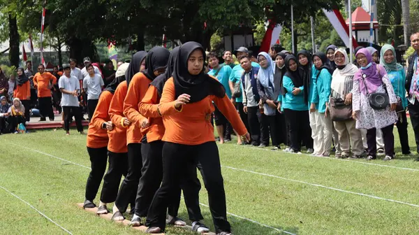Şenlikli kalabalık ve ulusal gururla heyecanlı bir takım oyunu. Erkekler, Endonezya Bağımsızlık Günü kutlamaları sırasında 14 Ağustos 2025 'te Pekalongan, Orta Java' da geleneksel bir bakiak yarışında yarışıyorlar..