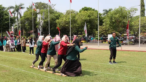 Şenlikli kalabalık ve ulusal gururla heyecanlı bir takım oyunu. Erkekler, Endonezya Bağımsızlık Günü kutlamaları sırasında 14 Ağustos 2025 'te Pekalongan, Orta Java' da geleneksel bir bakiak yarışında yarışıyorlar..