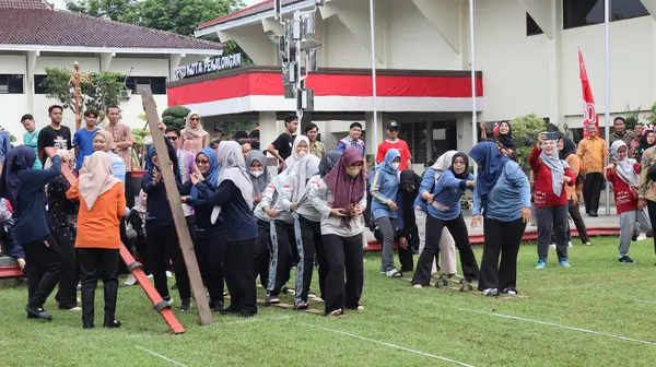 Şenlikli kalabalık ve ulusal gururla heyecanlı bir takım oyunu. Erkekler, Endonezya Bağımsızlık Günü kutlamaları sırasında 14 Ağustos 2025 'te Pekalongan, Orta Java' da geleneksel bir bakiak yarışında yarışıyorlar..