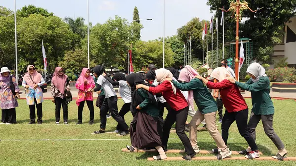 Şenlikli kalabalık ve ulusal gururla heyecanlı bir takım oyunu. Erkekler, Endonezya Bağımsızlık Günü kutlamaları sırasında 14 Ağustos 2025 'te Pekalongan, Orta Java' da geleneksel bir bakiak yarışında yarışıyorlar..