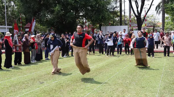 Şenlikli kalabalık ve ulusal gururla heyecanlı bir takım oyunu. Erkekler, Endonezya Bağımsızlık Günü kutlamaları sırasında 14 Ağustos 2025 'te Pekalongan, Orta Java' da geleneksel bir bakiak yarışında yarışıyorlar..