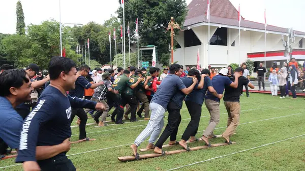 Şenlikli kalabalık ve ulusal gururla heyecanlı bir takım oyunu. Erkekler, Endonezya Bağımsızlık Günü kutlamaları sırasında 14 Ağustos 2025 'te Pekalongan, Orta Java' da geleneksel bir bakiak yarışında yarışıyorlar..