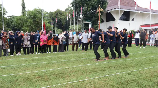 Şenlikli kalabalık ve ulusal gururla heyecanlı bir takım oyunu. Erkekler, Endonezya Bağımsızlık Günü kutlamaları sırasında 14 Ağustos 2025 'te Pekalongan, Orta Java' da geleneksel bir bakiak yarışında yarışıyorlar..
