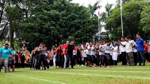 Şenlikli kalabalık ve ulusal gururla heyecanlı bir takım oyunu. Erkekler, Endonezya Bağımsızlık Günü kutlamaları sırasında 14 Ağustos 2025 'te Pekalongan, Orta Java' da geleneksel bir bakiak yarışında yarışıyorlar..