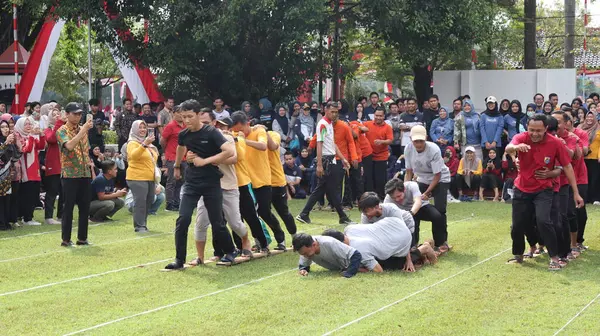 Şenlikli kalabalık ve ulusal gururla heyecanlı bir takım oyunu. Erkekler, Endonezya Bağımsızlık Günü kutlamaları sırasında 14 Ağustos 2025 'te Pekalongan, Orta Java' da geleneksel bir bakiak yarışında yarışıyorlar..