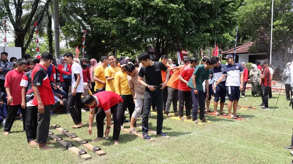 Şenlikli kalabalık ve ulusal gururla heyecanlı bir takım oyunu. Erkekler, Endonezya Bağımsızlık Günü kutlamaları sırasında 14 Ağustos 2025 'te Pekalongan, Orta Java' da geleneksel bir bakiak yarışında yarışıyorlar..