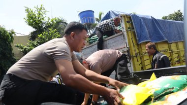 Polis memurları ve gönüllüler, 13 Ağustos 2025 tarihinde yerel halk Pekalongan, Endonezya 'yı desteklemek amacıyla hükümet gıda güvenliği programı kapsamında kamyonlardan pirinç yardımı indirip dağıtıyorlar.: