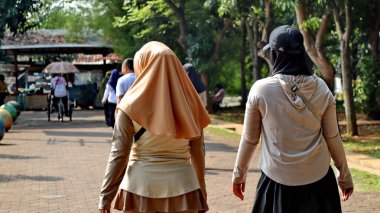 Şehir parkında ağaçlarla çevrili bir grup insan sabah aktivitesi, spor, sağlık, boş zaman ve toplum yaşam tarzı ile birlikte yürüyor. Rahat bir atmosfer. Pekalongan Endonezya, 14 Ağustos 2025