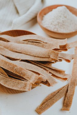 Beyaz bir masanın üzerinde tam tahıllı undan yapılmış el yapımı makarna kağıdı. Seçici odak.