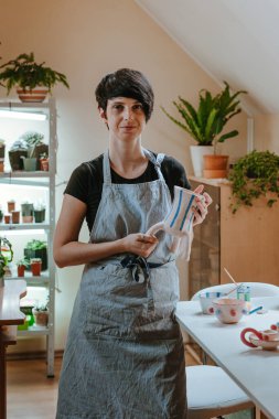 Atölyede vazo tutan genç bir kadın esnaf. Seçici odak.