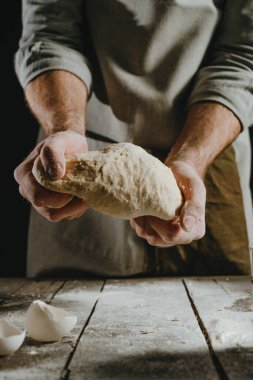 Siyah arka planda hamur tutan erkek eli yakın plan. Seçici odak.