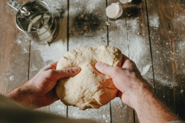 Siyah arka planda hamur tutan erkek eli yakın plan. Seçici odak, üst görünüm.