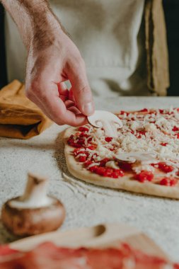 Şefin hamurun üzerine mantar koyarak pizza hazırladığı yakın plan. Seçici odak.