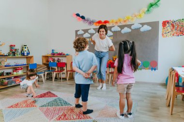 Anaokulunda çocuklarla oynayan genç bayan öğretmen. Seçici odak.