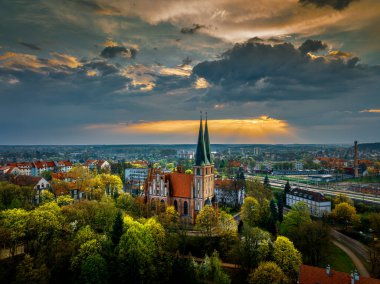 Polonya Kraliçemizin Garnizon Kilisesi, kalenin dışına kuş bakışı park edin. Kilisenin üzerinde, batan güneşin ışınları bulutları delip geçiyor. Yılın zamanı - İlkbahar.