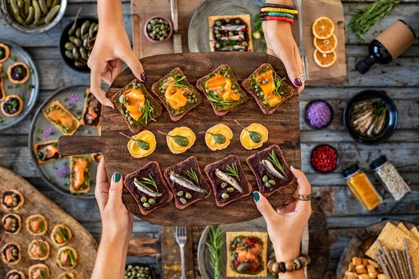 Stock image Sea food tapas and ricotta toast with capers at the hands of two women. Spanish food on the table. 