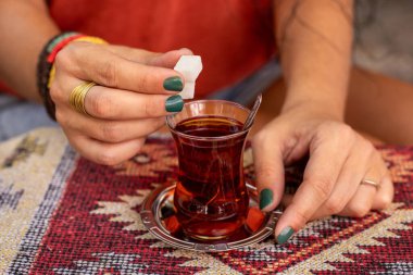 İnce bardakta Ajda adında bir Türk çayı. Elinde siyah çay olan bir kadın eli.. 