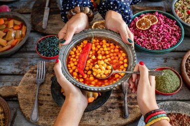 Masanın üzerinde domates sosu olan nohut tabağı. Bakır kasede vejetaryen yemeği. 