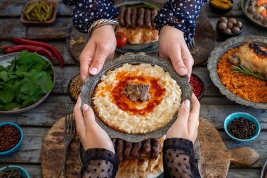 Geleneksel yemek Harry 'leri ya da Keskek' i yemek masasında elinde tutan iki kadının elleri. Buğday ve etle bir yemek.. 
