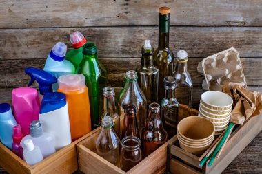 Masanın üzerinde birçok farklı türde geri dönüşüm var. Çeşitli kullanılmış cam şişeler, kavanozlar, saman, kağıt ve ampul.. 