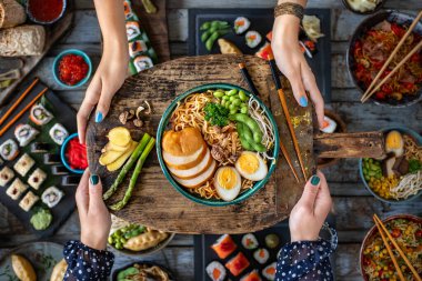 Ramen noodles at the hands of two women. Tonkotsu ramen bowl.  clipart