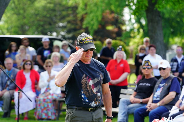 Marshfield, Wisconsin USA - May 29th, 2023: Male and female veterans salute to fallen soldiers graves during the Memorial Day ceremony.
