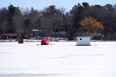 Green Lake, Wisconsin USA - 11 Şubat 2023: Buz tutmuş gölde buzda balık tutan insanlar.