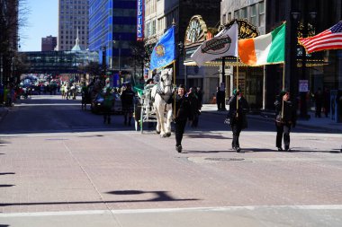 Milwaukee, Wisconsin USA - March 12th, 2022: A men dressed as Saint Patrick waved at spectators from his cart in St. Patrick's Day parade. clipart