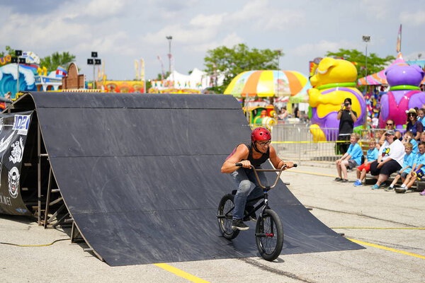 Fond du Lac, Wisconsin USA - 14 июля 2019 года: Велокаскадеры на BMX выполняют трюки на полутрубных пандусах для толпы людей на ярмарке округа Fond du Lac.