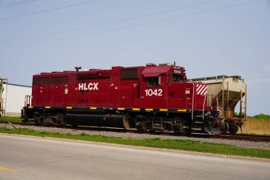 Green Bay, Wisconsin ABD - 18 Mayıs 2023: Red HLCX Helm Finansal Lokomotif tren motoru bir tren istasyonunda park halinde duruyor.