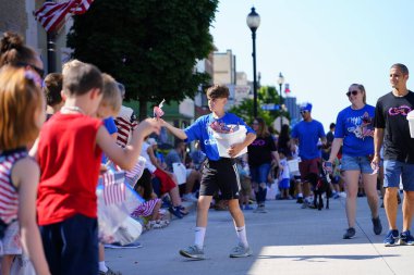 Sheboygan, Wisconsin ABD - 4 Temmuz 2019: Beytüllahim kilisesi ve yetişkin okulları ve Amerikan özgürlük renkleri giymiş çocuklar geçit töreninde izleyicilere şeker dağıtıyor