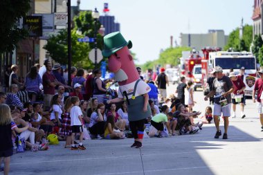 Sheboygan, Wisconsin ABD - 4 Temmuz 2019 Johnsonville sosis maskotu özgürlük yürüyüşünde yürüdü ve sokak kenarındaki çocukları selamladı..