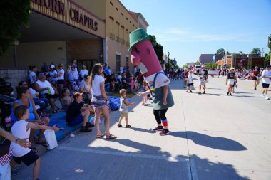 Sheboygan, Wisconsin ABD - 4 Temmuz 2019 Johnsonville sosis maskotu özgürlük yürüyüşünde yürüdü ve sokak kenarındaki çocukları selamladı..
