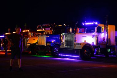 Waupun, Wisconsin ABD - 11 Ağustos 2023: Büyük kamyonlar ve yarı kamyonlar gece boyunca sarı uyarı ışıkları açık parladı.