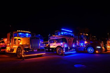 Waupun, Wisconsin ABD - 11 Ağustos 2023: Büyük kamyonlar ve yarı kamyonlar gece boyunca sarı uyarı ışıkları açık parladı.