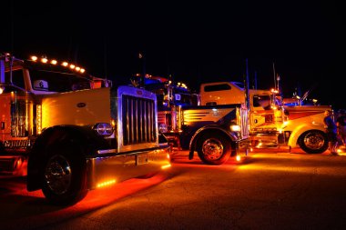 Waupun, Wisconsin ABD - 11 Ağustos 2023: Büyük kamyonlar ve yarı kamyonlar gece boyunca sarı uyarı ışıkları açık parladı.