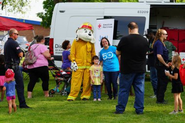 Fond du Lac, Wisconsin ABD - 22 Ağustos 2019: Genç çocuklar, kostümlü bir itfaiye köpeğine sarılıp etkileşime giriyorlar.