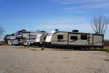 Bir sıra beyaz karavan ormanda yere park etmiş..