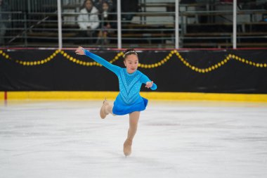 Mosinee, Wisconsin ABD - 26 Şubat 2021: Güzel mavi elbiseli Asyalı yetişkin kadın porsuk eyaleti buz pateni yarışmasına katıldı