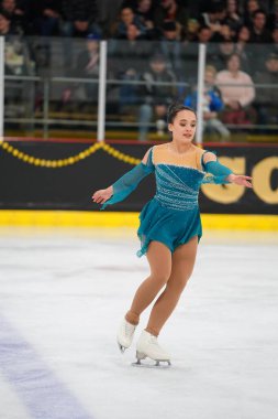 Mosinee, Wisconsin ABD - 26 Şubat 2021: Porsuk eyaleti buz pateni yarışmasına katılan turkuaz elbiseli yetişkin kadın